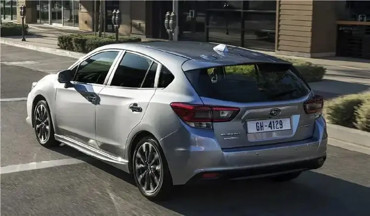 Parte trasera de New Impreza color plata, en calle de ciudad con acera de fondo